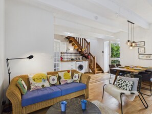 Ein zeitgemäßer Wohnraum mit Sofa, Esstisch und einer Treppe, die in ein Obergeschoss führt.