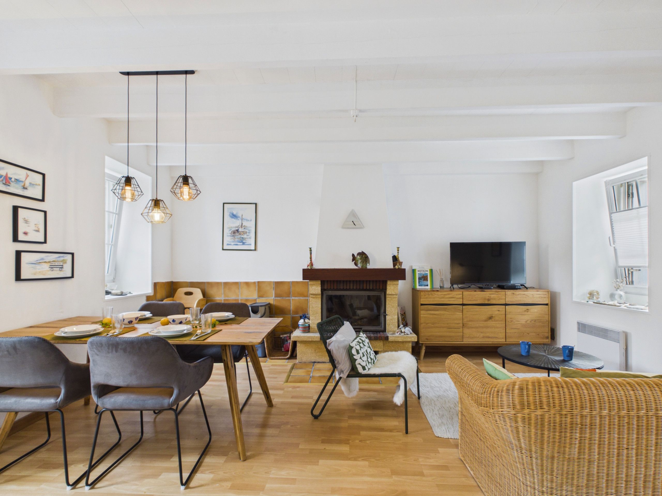A modern living room with a dining area, a fireplace, and a television.