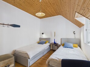 Ein Schlafzimmer mit zwei Betten, einer Holzbalkendecke und einem Fenster.