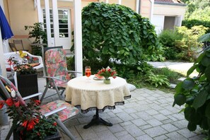 A patio with a round table, chairs, and a decorative hedge. - Seesternchen - Residence under the Linden trees (Kühlungsborn)