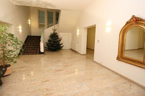 A spacious room with a tiled floor, a staircase, a Christmas tree, and a large mirror. - Seesternchen - Residence under the Linden trees (Kühlungsborn)