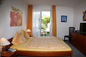 Een hotelkamer met een bed, een bureau, een stoel, een televisie en een raam met gordijnen.