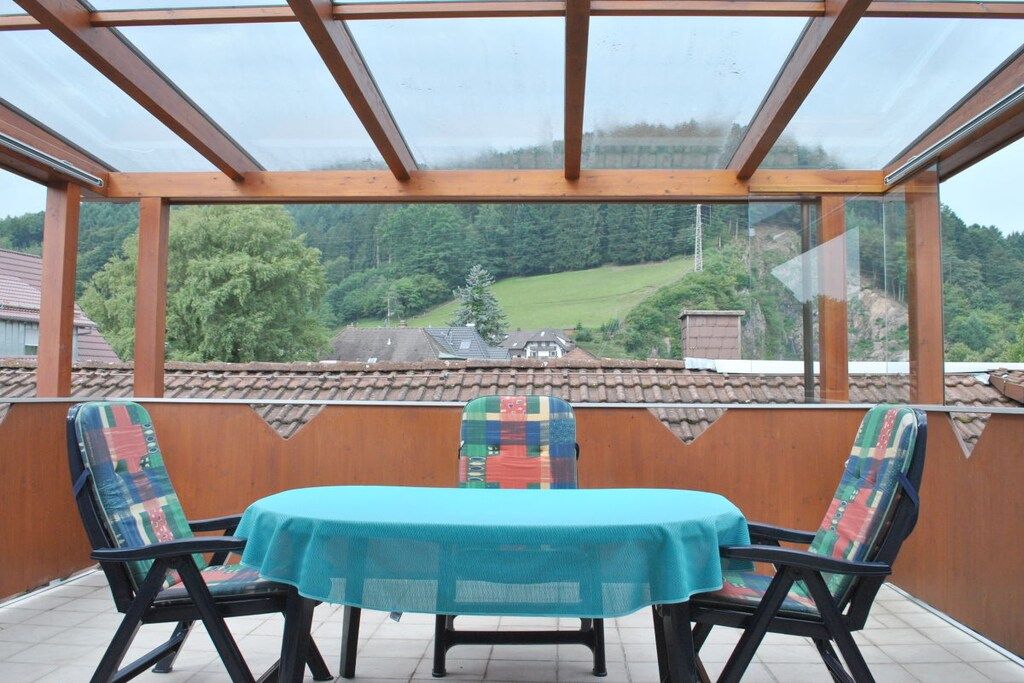 A covered patio with a table and chairs, overlooking a rural landscape.