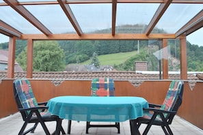 Eine überdachte Terrasse mit Tisch und Stühlen mit Blick auf eine ländliche Landschaft.