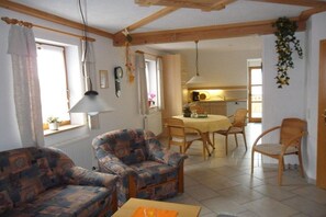 A living room with a sofa, chairs, a table, and a kitchen in the background. - Holiday farm Kleeblatt (Westheim)