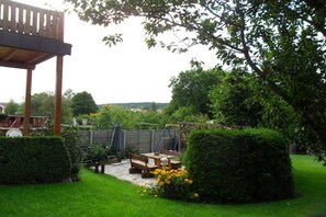 A patio area with a wooden table and benches, surrounded by well-maintained hedges and a view of a residential area. - Holiday farm Kleeblatt (Westheim)