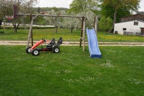 A playground with a swing set, a slide, and a tricycle. - Holiday farm Kleeblatt (Westheim)