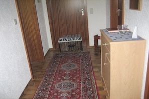 Ein Flur mit einem gemusterten Teppich, einem Holzschrank und einem Korb gefalteter Handtücher.