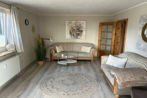 A living room with a sofa, a coffee table, a patterned rug, and a painting on the wall. - Holiday apartment with 1 bedroom (Langballigau)