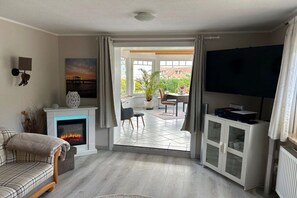 Een woonkamer met een open haard, een televisie en uitzicht.