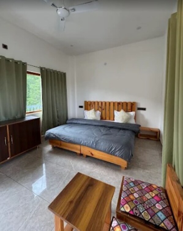 A bedroom with a bed, a wooden headboard, a bedside table, a bench, and a window with curtains.