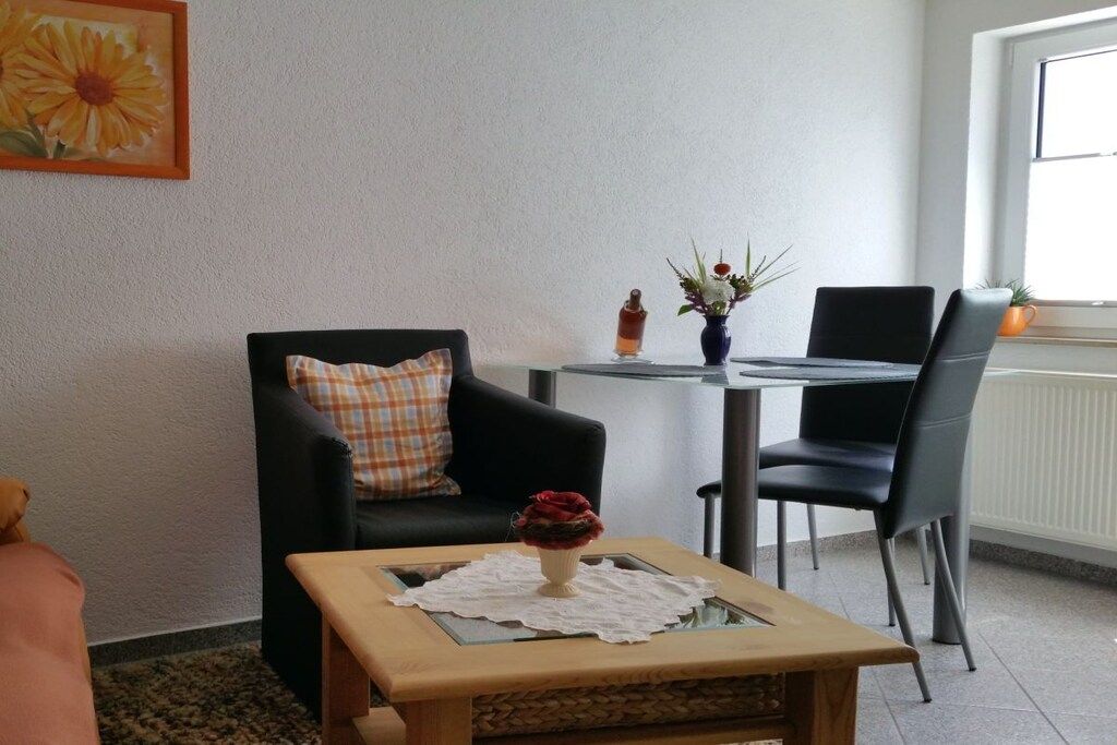 Un salon comprenant un canapé, une table basse, une petite table avec des chaises et une fenêtre donnant sur un paysage agréable.