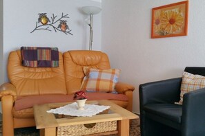 A living room with a sofa, a coffee table, and a black armchair. - Holiday apartment with 1 bedroom (Schleusingen OT Hinternah)