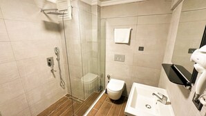 A modern bathroom with a glass-enclosed shower, a toilet, and a sink with a mirror. - GRAND PALACE HOTEL (Bartın)