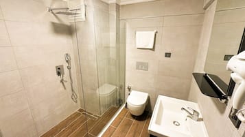 Un baño moderno con ducha de vidrio, inodoro y lavamanos con espejo.
