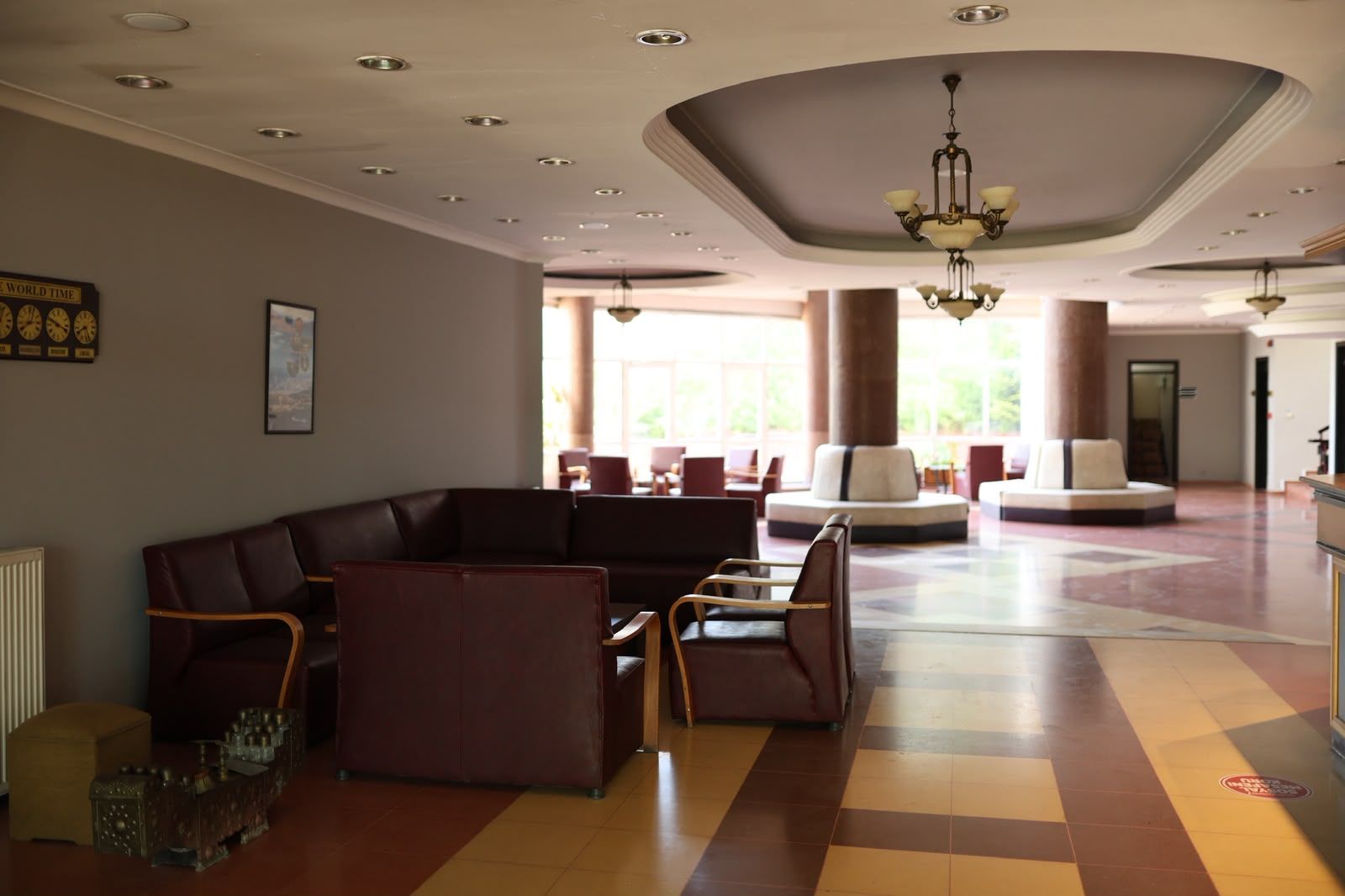 A lobby with a checkered floor, a seating area with sofas and chairs, a chandelier, and a large pillar.