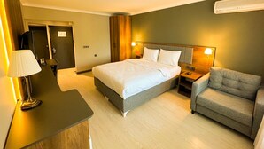 A hotel room with a bed, bedside tables, a lamp, a chair, and a wardrobe. - GRAND PALACE HOTEL (Bartın)
