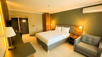 Una habitación de hotel con cama, mesitas de noche, lámpara, silla y armario.