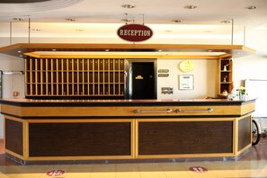 A reception desk with a sign, a door, and a wall-mounted plaque. - GRAND PALACE HOTEL (Bartın)
