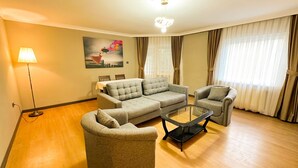 A living room with a sofa set, a glass coffee table, and a lamp. - GRAND PALACE HOTEL (Bartın)