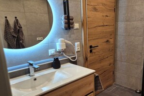 A bathroom with a white sink, a mirror, a towel rack, and a wooden door.