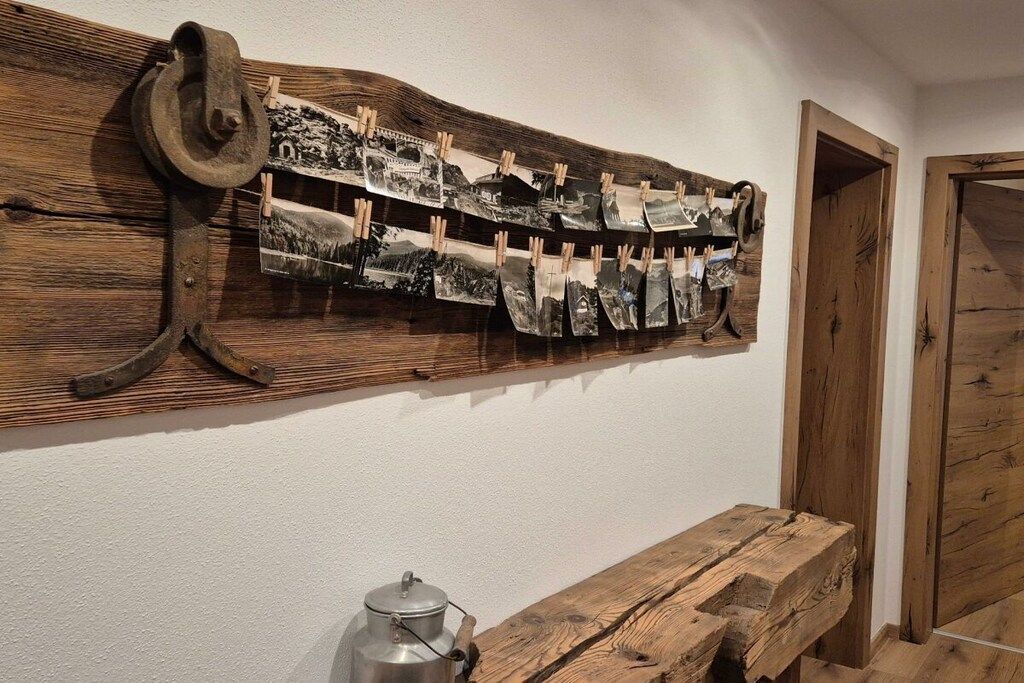 A rustic wooden wall with a series of black-and-white photographs displayed on a wooden rack.