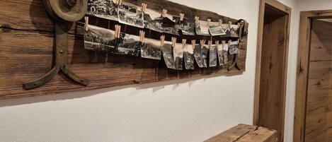 A rustic wooden wall with a series of black-and-white photographs displayed on a wooden rack.