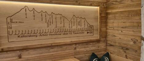 Una pared de madera con un mapa del perfil de una montaña y un indicador direccional.