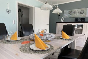 Ein Essbereich mit einem Tisch, der für vier Personen gedeckt ist, einschließlich Geschirr, Servietten und Gläsern.