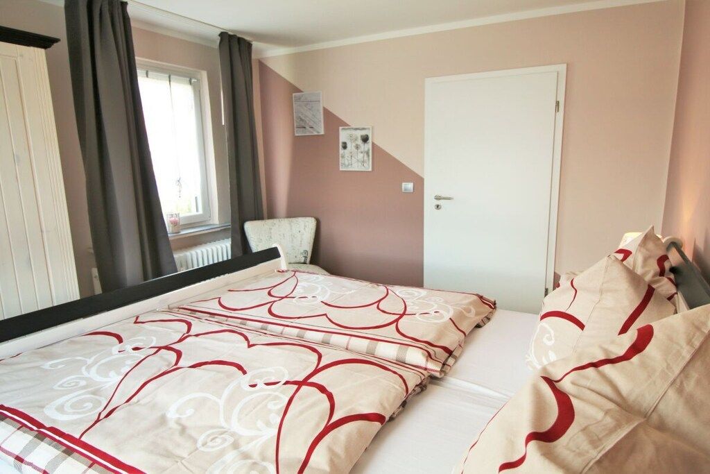 A bedroom with a bed, a window, a door, and a wall with two pictures.
