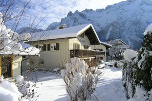 Ein Chalet-Stil Gebäude mit geneigtem Dach, umgeben von schneebedeckten Bergen.
