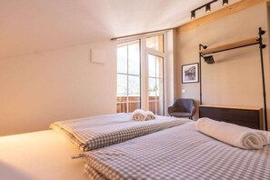 A hotel room with two beds, a chair, a wooden headboard, and a window with a view. - Anuk House Holiday home with mountain views (Farchant)
