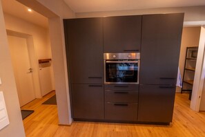 A modern kitchen with a built-in oven and a dark-colored cabinet structure. - Anuk House Holiday home with mountain views (Farchant)