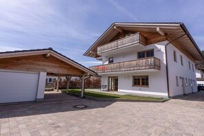 A two-story building with a covered patio area and a garage. - Anuk House Holiday home with mountain views (Farchant)