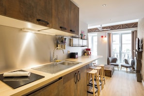 Una cocina moderna con estufa integrada, pileta y muebles de madera. Hay una zona de comedor con mesa y sillas, además de un balcón con vistas.