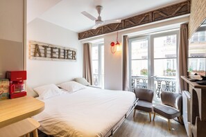 Ein Hotelzimmer mit Bett, einer Kaffeemaschine, einem Sessel, Balkonblick und Deckenventilator.