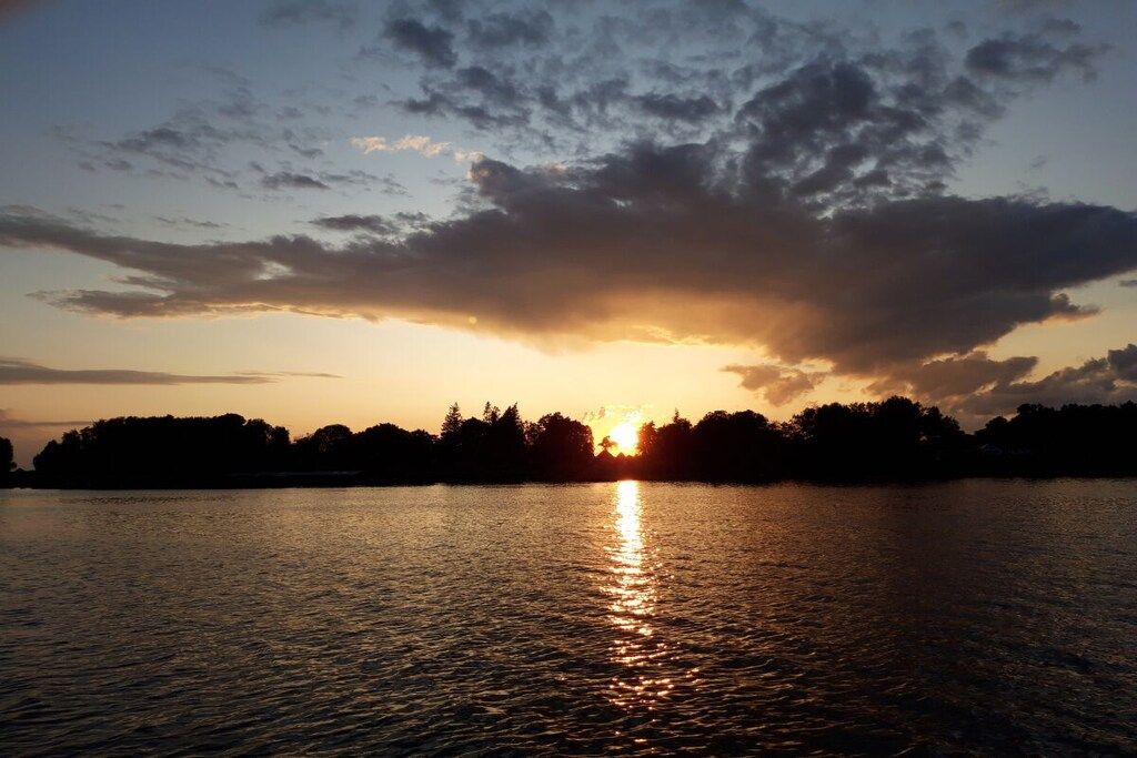 A sunset over a body of water with a silhouette of trees in the background.
