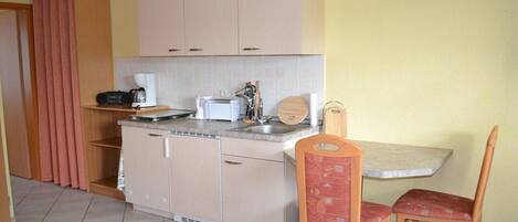 Cocina compacta con lavamanos, encimera y zona de comedor con dos sillas.