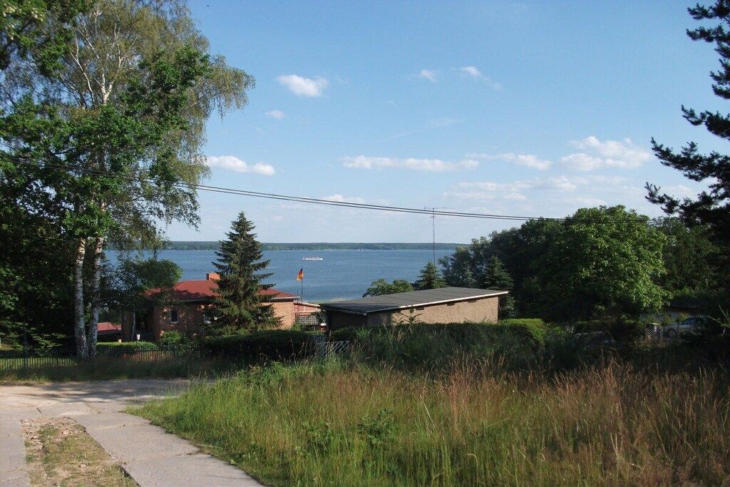 A residential area with a view of a lake, a small building, and a paved path.