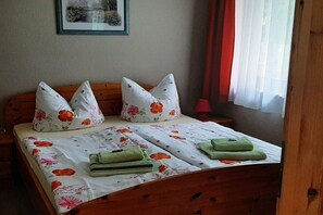 En säng med blommigt sänglinne, två kuddar och två hopvikta handdukar.
