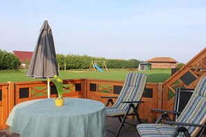 Eine Außenpatio mit einem runden Tisch, einem gestreiften Stuhl und einem Sonnenschirm.