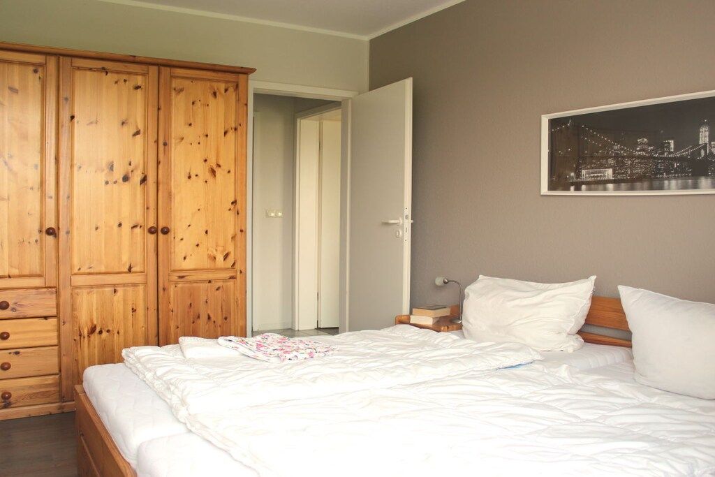 A bedroom with a bed, wooden wardrobe, and a cityscape picture on the wall.