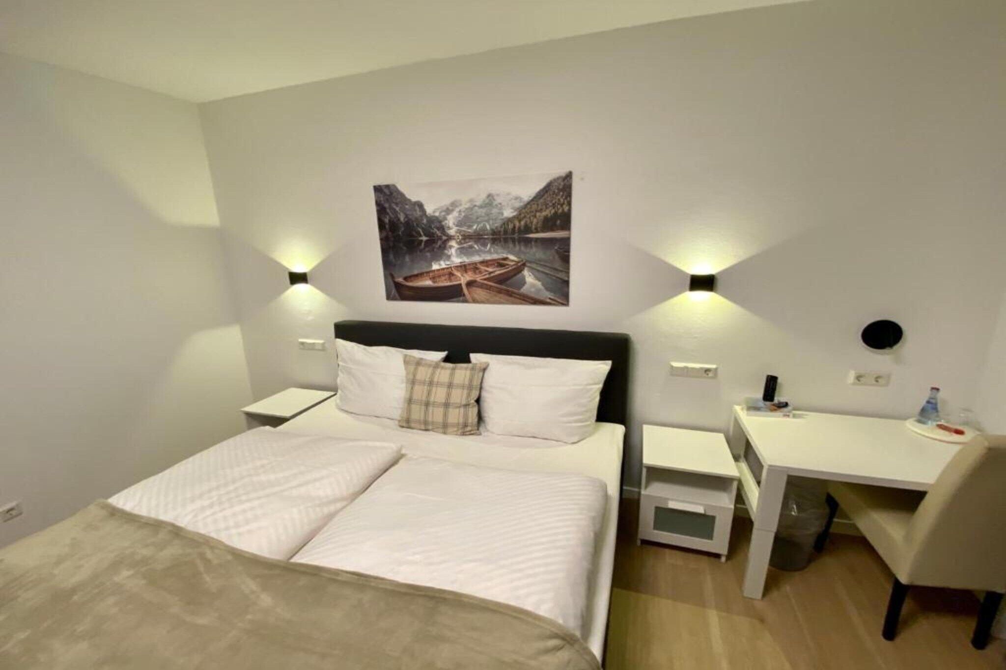 Een slaapkamer met een bed, nachtkastjes, een bureau en een stoel.