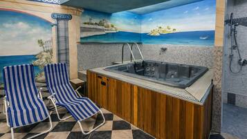 A bathroom with a bathtub, a shower, and a seating area with striped chairs.