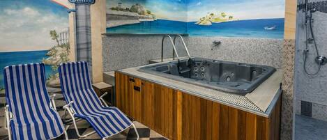 A bathroom with a bathtub, a shower, and a seating area with striped chairs.
