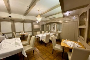 A dining area with multiple tables set for guests, chairs, and a chandelier. - Landhotel Rauber Sankt Wendel Double Room (Oberthal)
