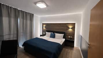 A hotel room with a bed, a nightstand, a chair, and a door.
