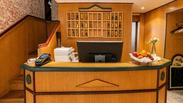 A reception desk with a computer, a phone, and a fruit basket.