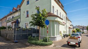 Eine Wohnstraße mit einem zweistöckigen Gebäude, einem blauen Schild und geparkten Autos.