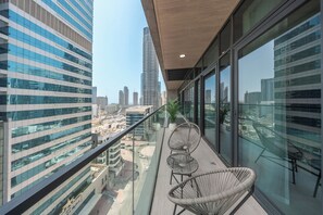 A balcony with a glass railing overlooking a cityscape, featuring modern buildings and a clear sky. - StayShort - Chic 1 Bedroom Unit in Dubai Marina that Sleeps 4! (Dubai)